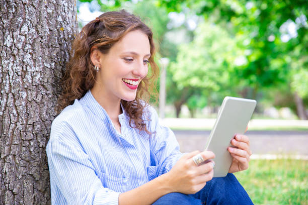 istock Happy young woman talking via telecommunication app on tablet 1155840506