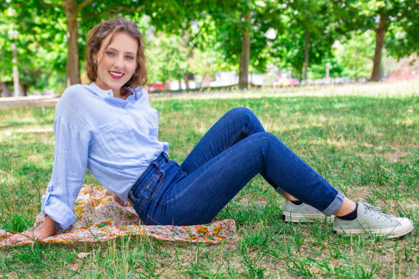 istock Smiling beautiful girl sitting on ground in park 1155840536