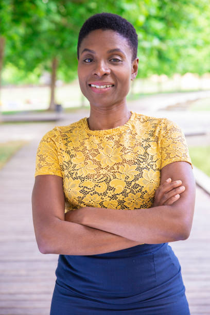 istock Smiling confident black lady standing in city park 1155840553