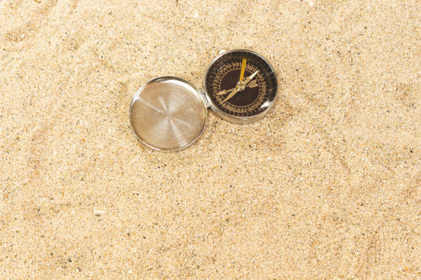 失われたか方向のためのビーチの概念の砂のコンパス - compass direction east gold ストックフォトと画像