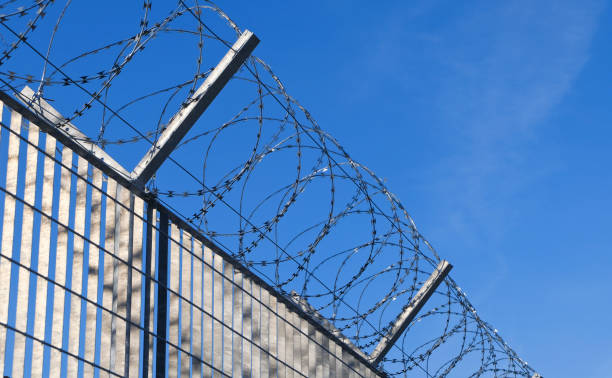 the fence - razor wire at the border - black and white architecture surrounding wall wall imagens e fotografias de stock