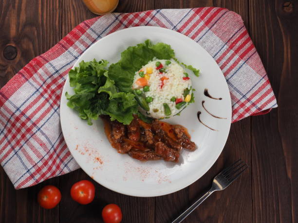 istock Roasted meat, white rice and vegetables on wooden table 1155842825