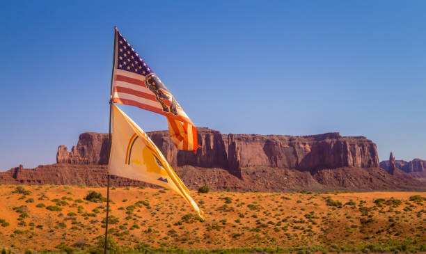 flagge des amerikanischen indianerstammes navajo vor dem hintergrund der landschaft des monument valley in arizona - navajo national monument stock-fotos und bilder