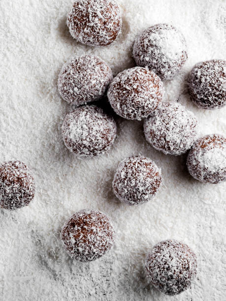 trüffel, schokoladenbonbons mit kokosflocken, rohschokolade-tüffeln, unvergesüßte kokosnuss-energiebände mit schokolade, - powdered coconut stock-fotos und bilder