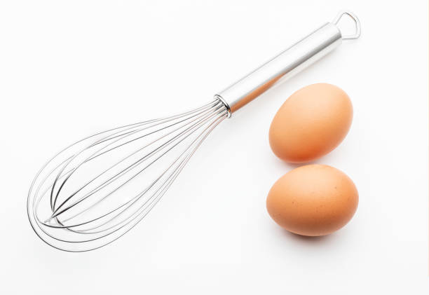 istock Metallic kitchen rods for manually mixing food with 2 fresh eggs (collection of cooking objects). Isolated on white background. 1155845531