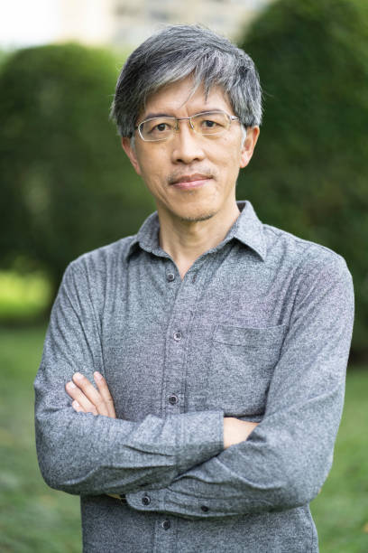 istock Asian man standing arms crossed in park 1155846673