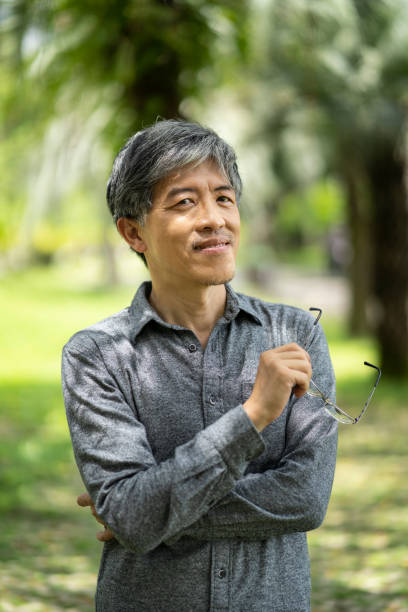 istock Asian man standing arms crossed in park 1155846715