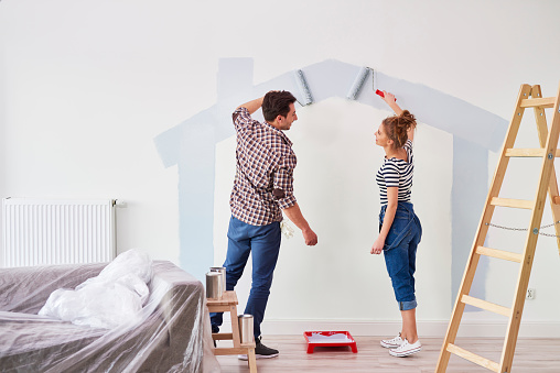 Pareja joven pintando la pared interior en su nuevo apartamento photo