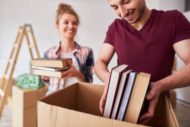 istock Young couple packing books into box 1155850909