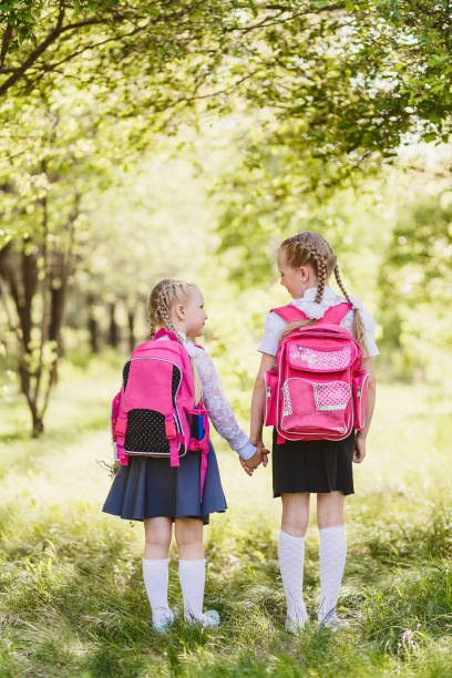 istock girls in school uniform and with backpacks stand back 1155851468