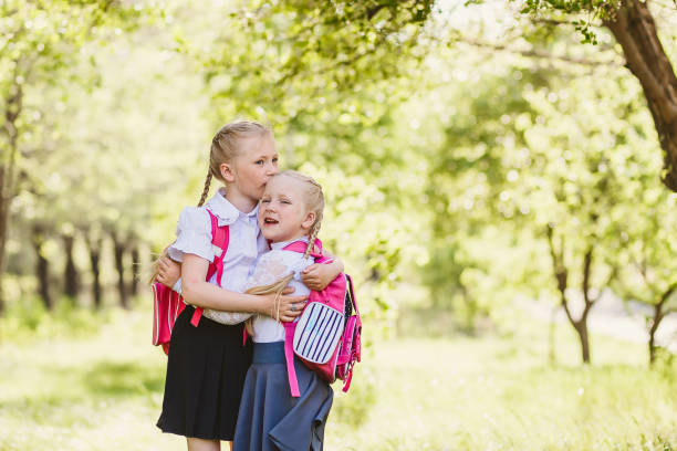 istock cute blonde girls in school uniform hugging 1155851516