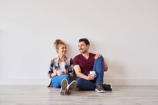 coppia sorridente con caffè che si prende una pausa dal trasferirsi a casa - floor sitting foto e immagini stock