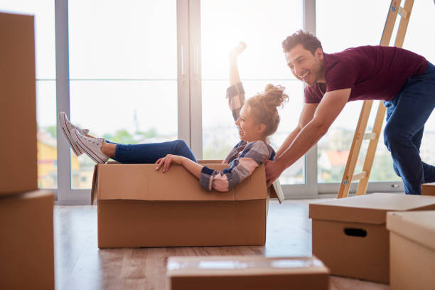 istock Playful couple having fun with boxes during move house 1155854126