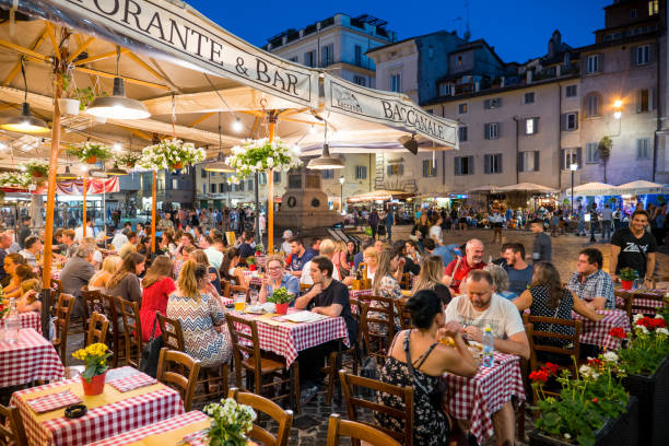Dozens of tourists enjoy Italian cuisine in a lovely restaurant in Campo de Fiori in the heart of Rome Rome, Italy, Jun 12 - A night scene among the restaurants of the famous Campo de Fiori square, one of the most loved and visited by tourists, located in the heart of Rome between Piazza Farnese and Piazza Navona. The square is the scene of the Roman "movida", with the presence of numerous restaurants of Italian cuisine, pubs and cafes. Rome nightlife stock pictures, royalty-free photos & images