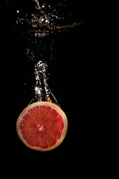 Grapefruit falls into the water on a black background
