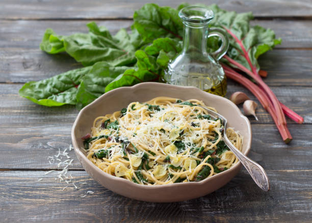istock Delicious spaghetti with chard, garlic and cheese on a wooden table 1155856106