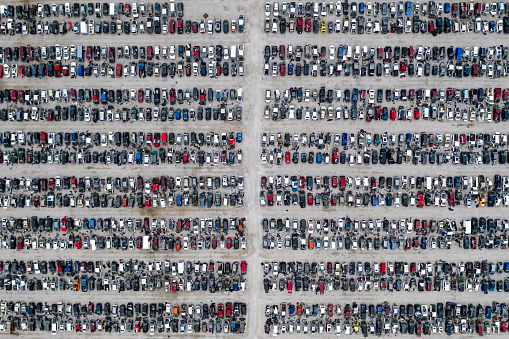 A large junkyard with hundreds of wrecked cars in rows, aerial view.