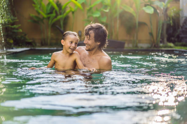 istock Dad and son have fun in the pool 1155857672