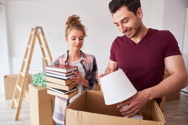istock Couple packing books and lamp to the boxes 1155858112