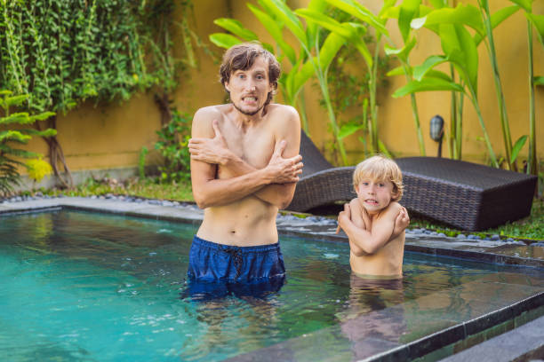 papá y su hijo estaban congelados en la piscina. agua muy fría en la piscina. necesidad de agua caliente - human face water washing women fotografías e imágenes de stock