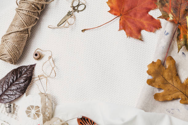 istock Scissors, thread and fallen leaves lie on white cloth 1155862401