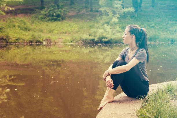 istock Beautiful woman meditating by the water 1155863255