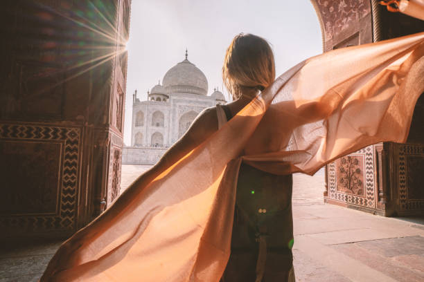 Happy young woman walking and wandering at the famous Taj Mahal at sunrise holding scarf in hands, Agra, India. People travel Asia concept Happy young woman walking and wandering at the famous Taj Mahal at sunrise holding scarf in hands, Agra, India. People travel Asia concept pashmina stock pictures, royalty-free photos & images