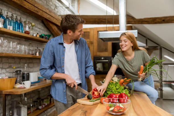 istock Lovely cheerful young couple cooking dinner together 1155865582