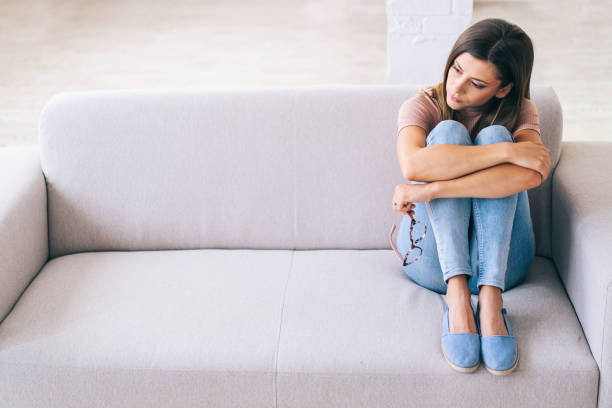 Sad woman sitting on a sofa at home