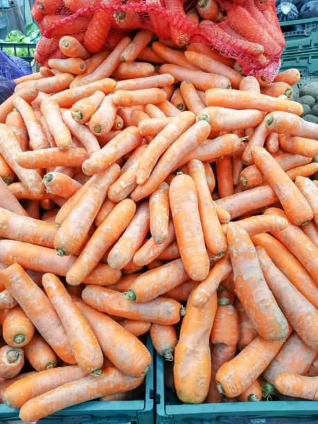 istock Fresh yellow carrots in cardboard boxes on the store shelf 1155866631