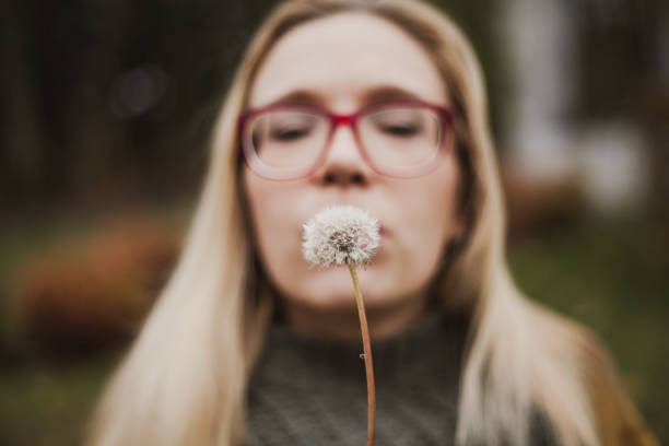 istock Slender blonde with long hair blowing on dandelion 1155866818