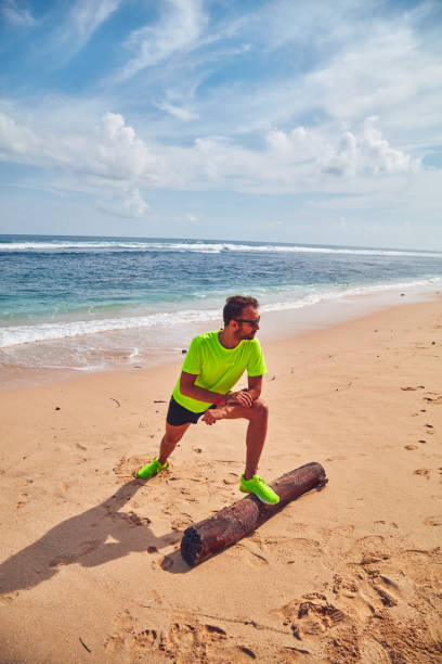 istock Sportsman stretching on a tropical sandy beach. 1155867479