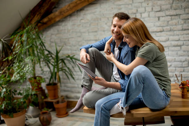 istock Young couple is using a digital tablet and smiling in kitchen at home 1155867599