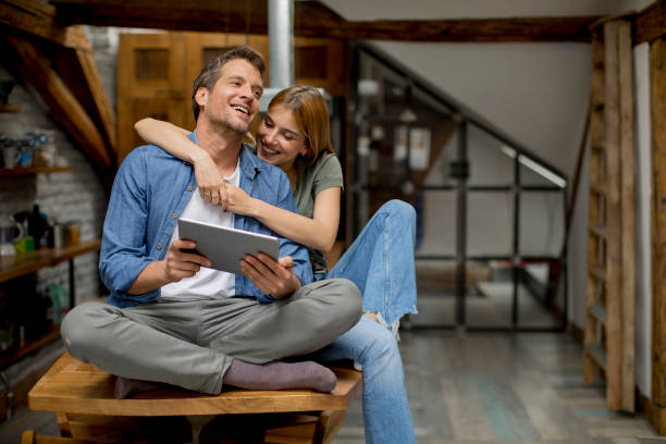 istock Young couple is using a digital tablet and smiling in kitchen at home 1155867602
