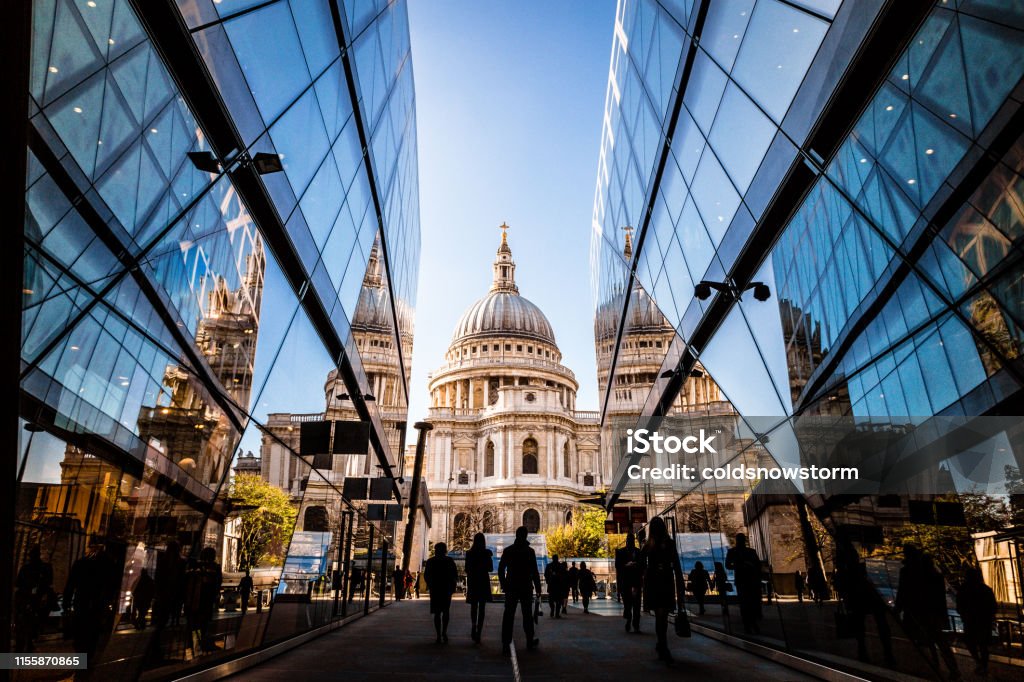 Urban crowd and futuristic architecture in the city, London, UK Color image depicting a crowd of people, thrown into silhouette and therefore unrecognisable, walking alongside modern futuristic architecture of glass and steel. In the distance we can see the ancient and iconic dome of St Paul's cathedral. Room for copy space. London - England Stock Photo
