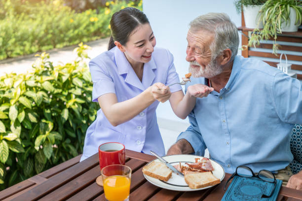 istock Nurse feeding elderly senior man to eat breakfast at nursing home 1155876350