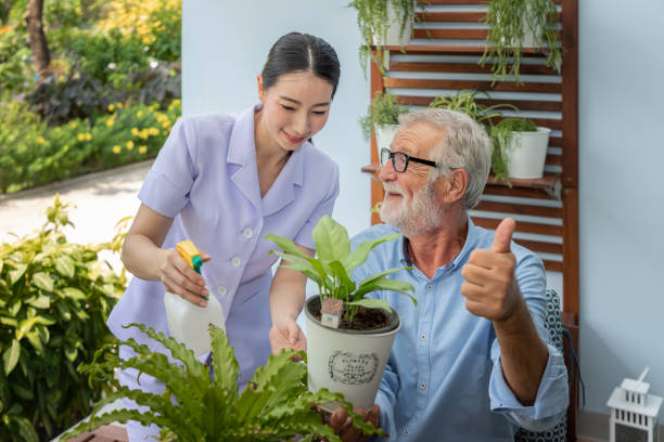 istock Caregiver help assist senior old man eldery puring water and taking care small tree on table thumb up 1155876388