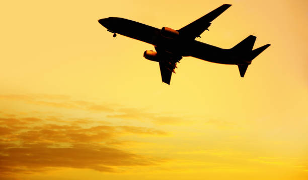 istock flying commercial passenger airplane over orange colored sunset sky 1155879326