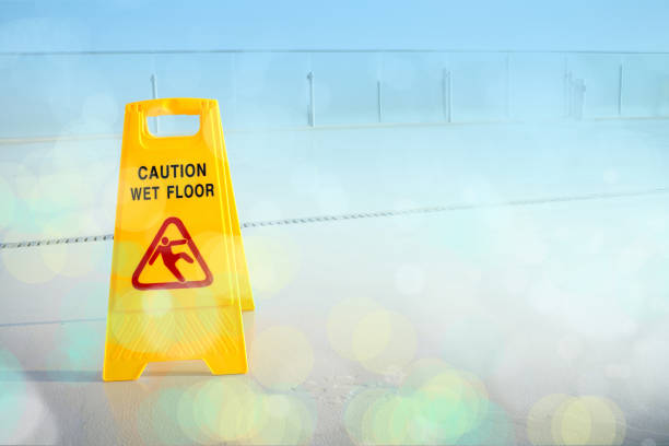 Close up yellow wet floor sign on wet floor with abstract light reflections on building terrace