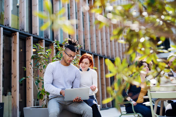 Group of young businesspeople using laptop in courtyard, start-up concept.