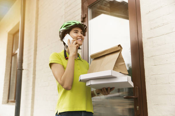 istock Young woman as a courier delivering pizza using gadgets 1155884018