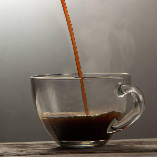 istock Pouring coffee into cup with splashing on brown background. 1155888030