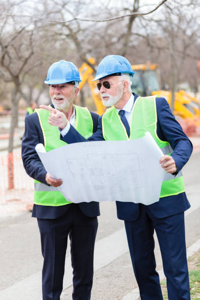 two senior engineers or businessmen visiting construction site, looking at blueprints and discussing - 16607 imagens e fotografias de stock