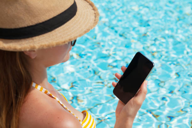 istock Young woman using smartphone near a swimming pool 1155890257