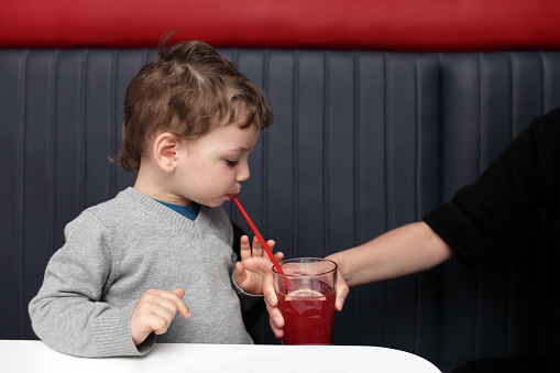 Mother giving juice to her son in the cafe
