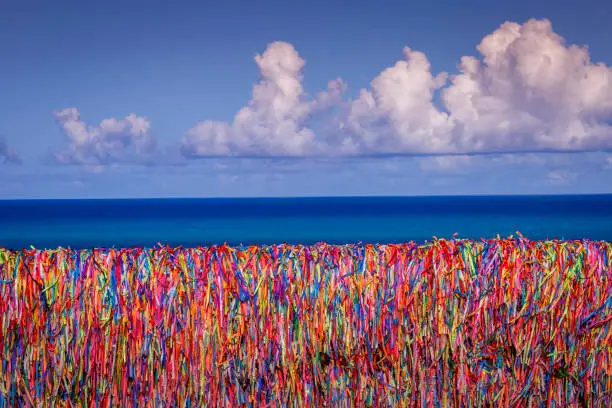 Colorful Bonfim wish ribbons on a wall and turquoise beach in Porto Seguro - Bahia, northeast Brazil