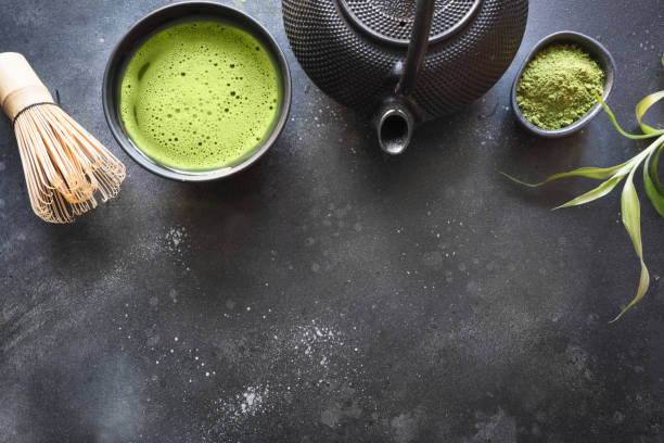 istock Ceremony green matcha tea and bamboo whisk on black table. Top view. Space for text. 1155901872