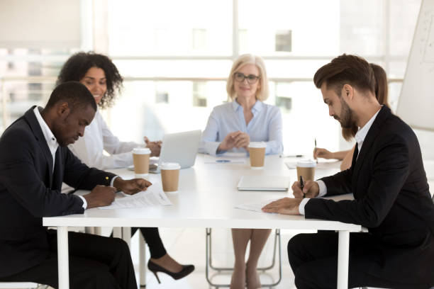 istock Smiling diverse employees looking at new workers signing contract 1155902215