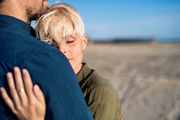 istock Midsection of young couple standing outdoors on beach, hugging. Copy space. 1155902329