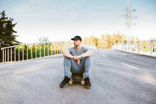istock Young man sitting on his longboard. 1155904467